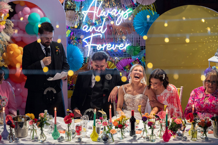 Bride and groom laugh at top table during wedding speeches