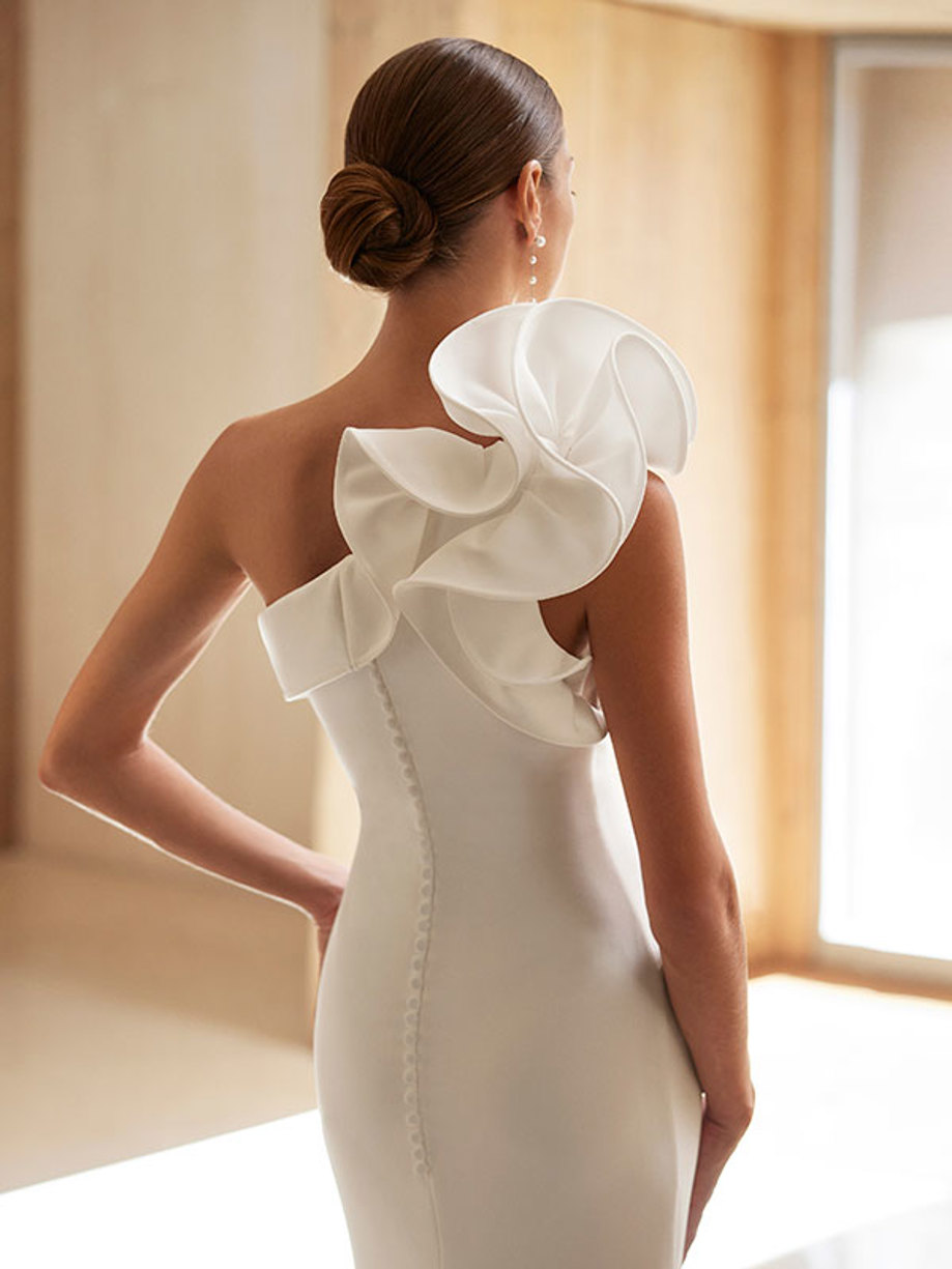 back close up of a brunette woman in a white gown with one prominent signature sleeve 