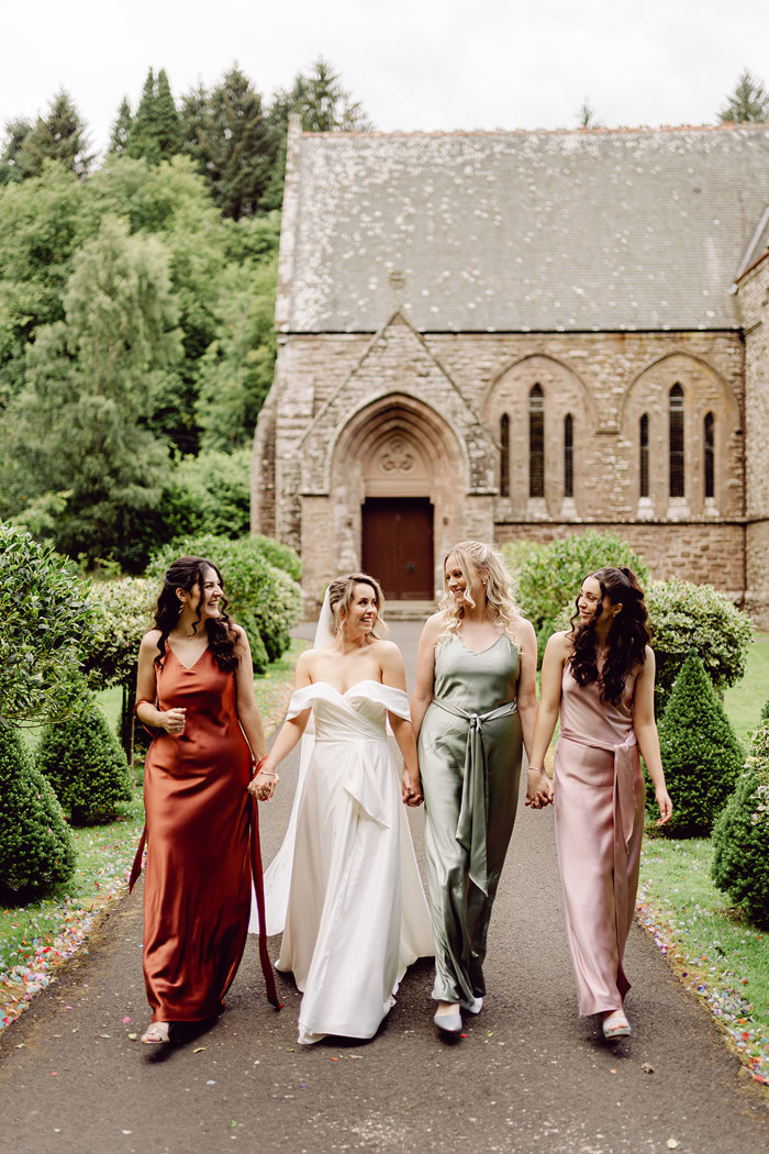 bride walks towards camera with bridesmaids at either side at drumtochty castle