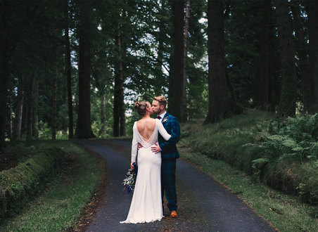 A bride and groom kissing in a forest
