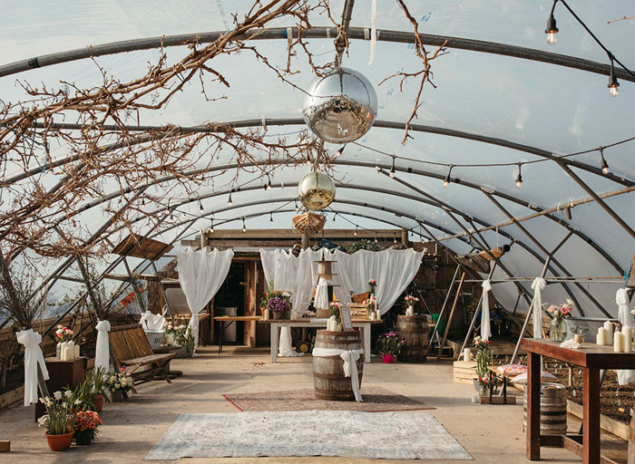 a poly tunnel decorated for a wedding with white draped curtains, disco balls and wedding decorations