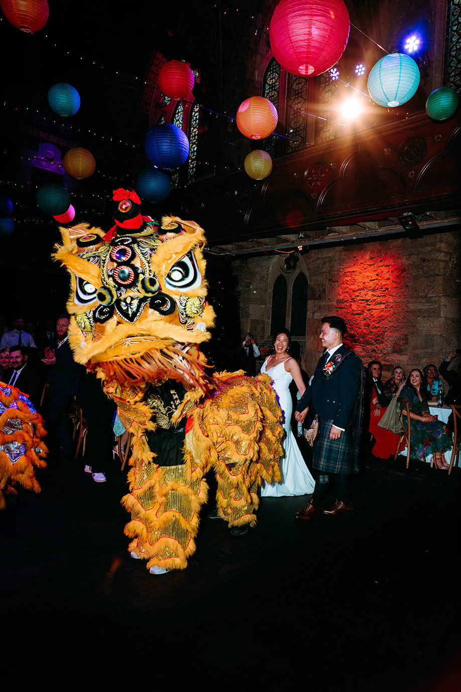 a yellow and gold large Chinese dragon or lion puppet with bride and groom in background