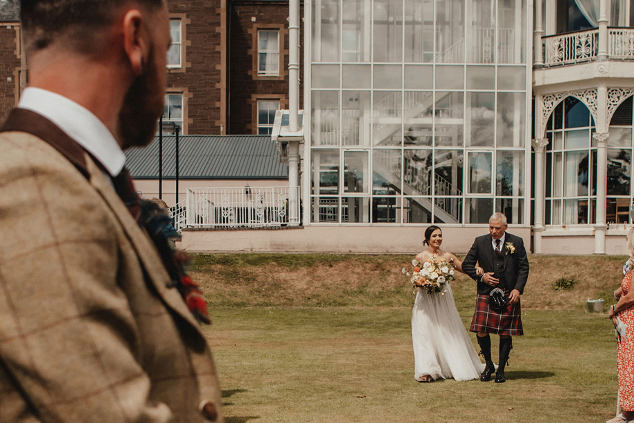 Groom watches bride and her father walk down the aisle