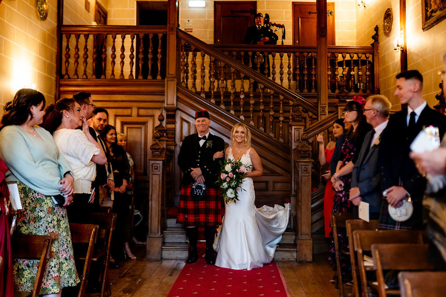  bride walking down the aisle with her dad wearing a kilt at wedding at dalhousie castle