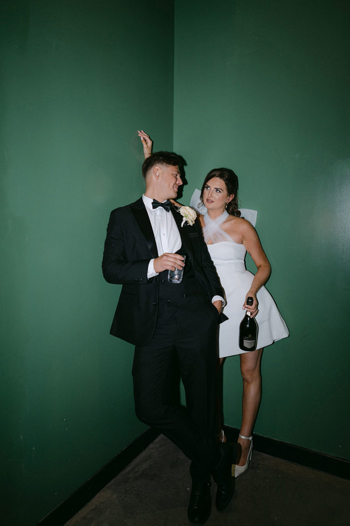 A bride and groom posing for a picture against a green wall at the Engine Works