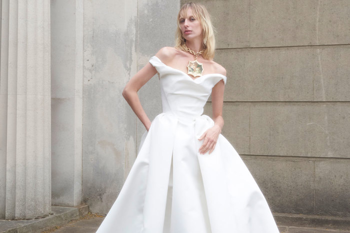 blonde woman in structured off the shoulder ballgown wedding dress and large chunky pendant necklace