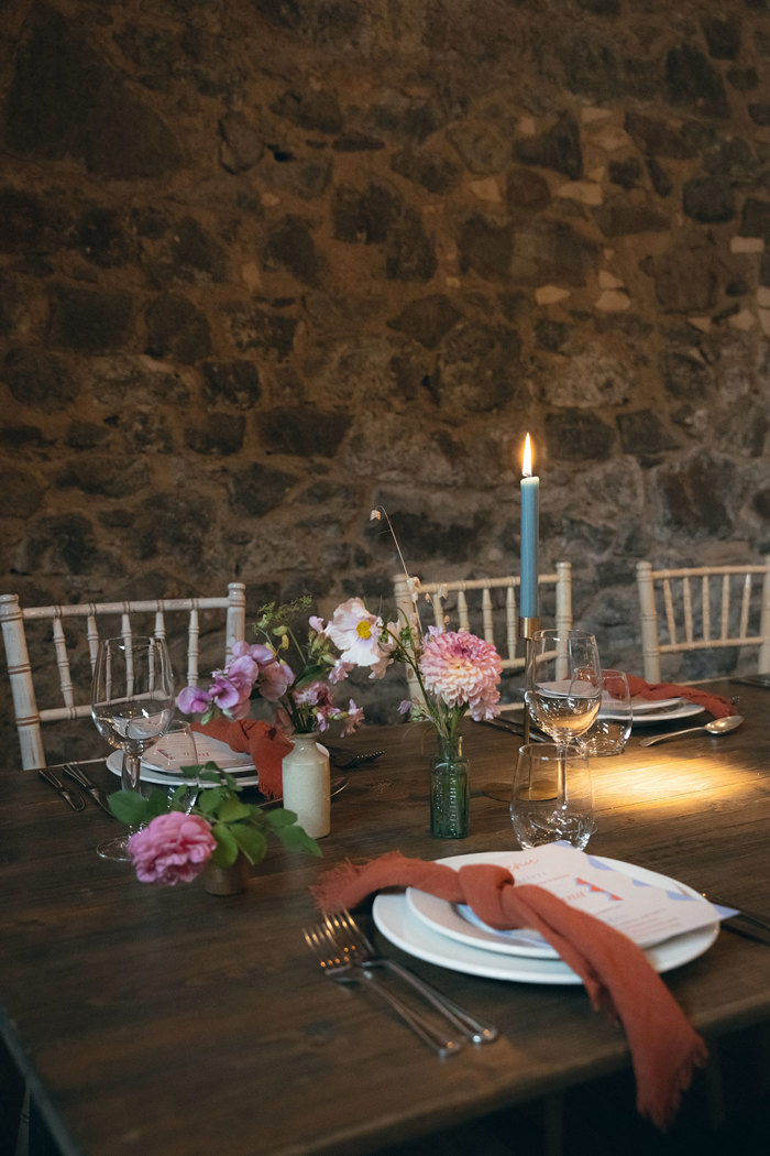 A table set up for a wedding with flower arrangements in bottles.