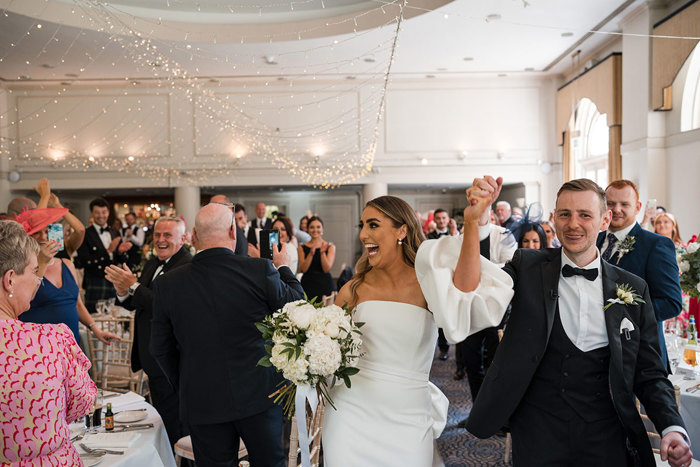 A happy couple entering their reception