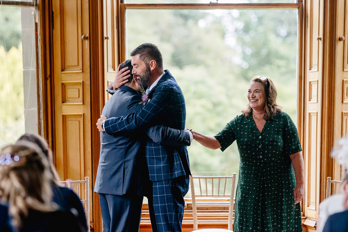 Grooms embrace during wedding ceremony