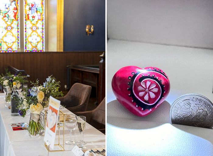 wedding table detail with stained glass window in background on left. A painted red heart next to a coin on right.