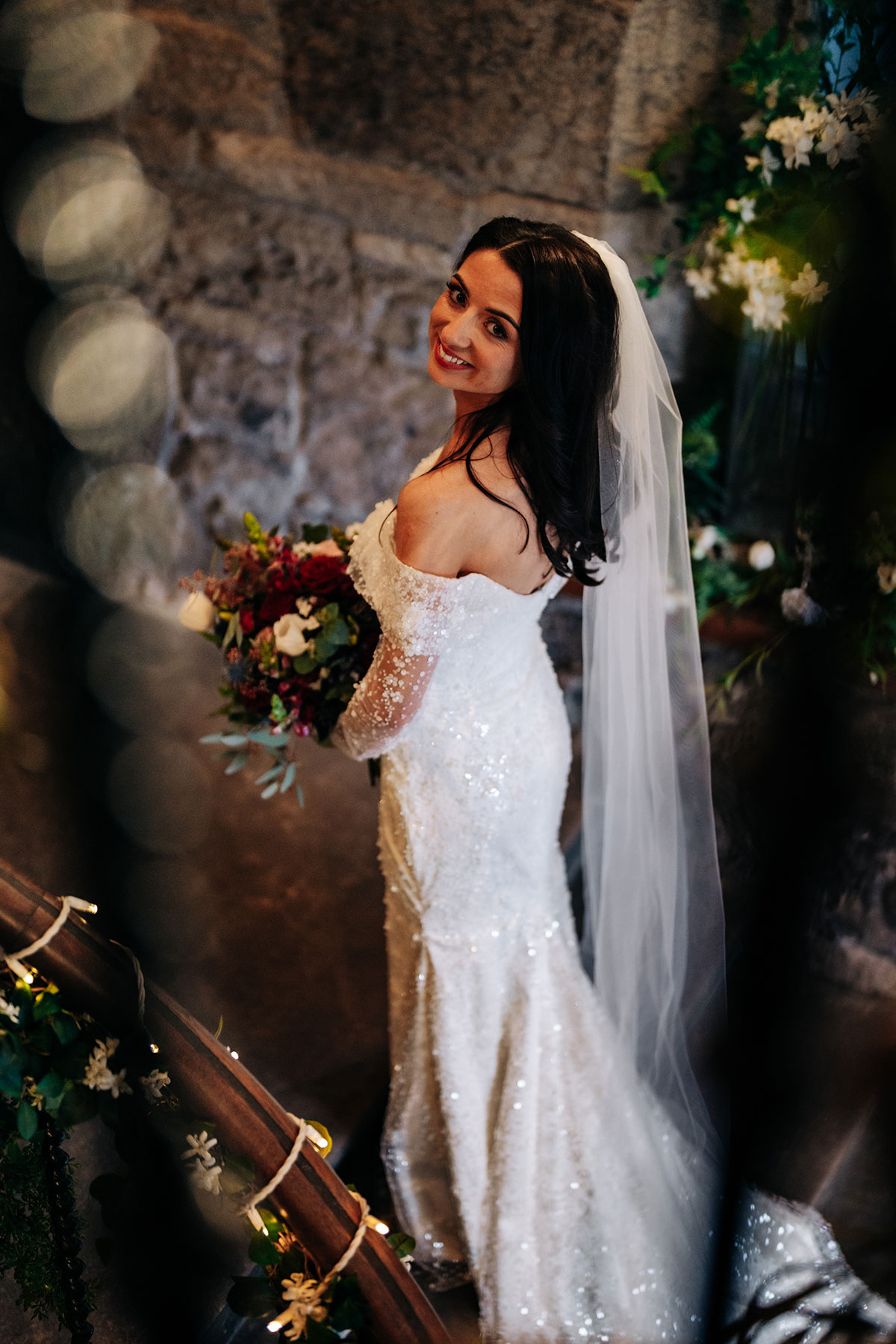 bride smiles towards camera as she wears sparkly wedding dress and veil