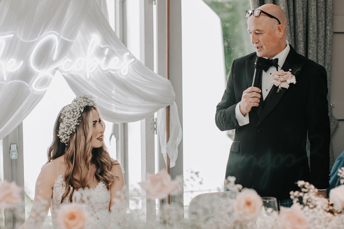 The bride watches her father deliver his speech