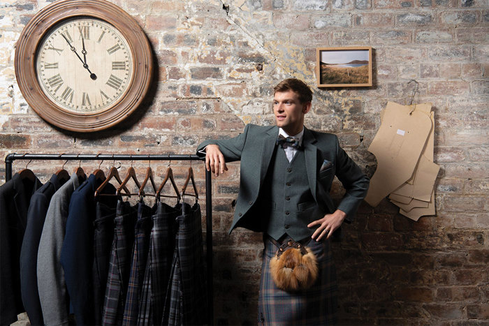 Man standing in kilt next to rail of kilts