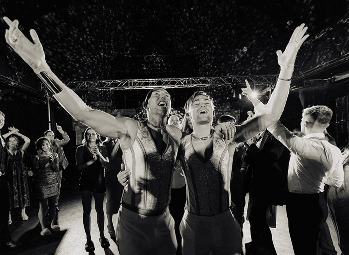 black and white image of grooms embracing holding one arm out