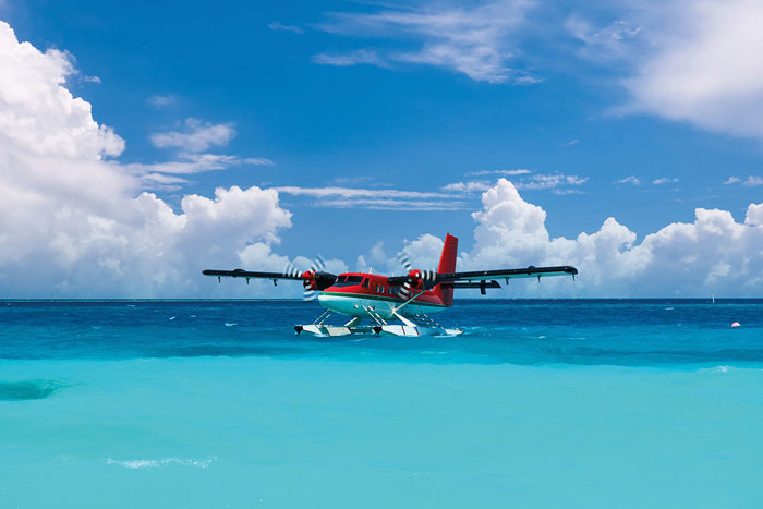 a red sea plane skimming the surface of a crystal blue ocean