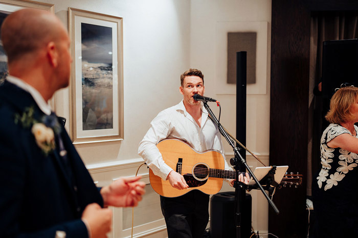 a person playing guitar standing behind a microphone