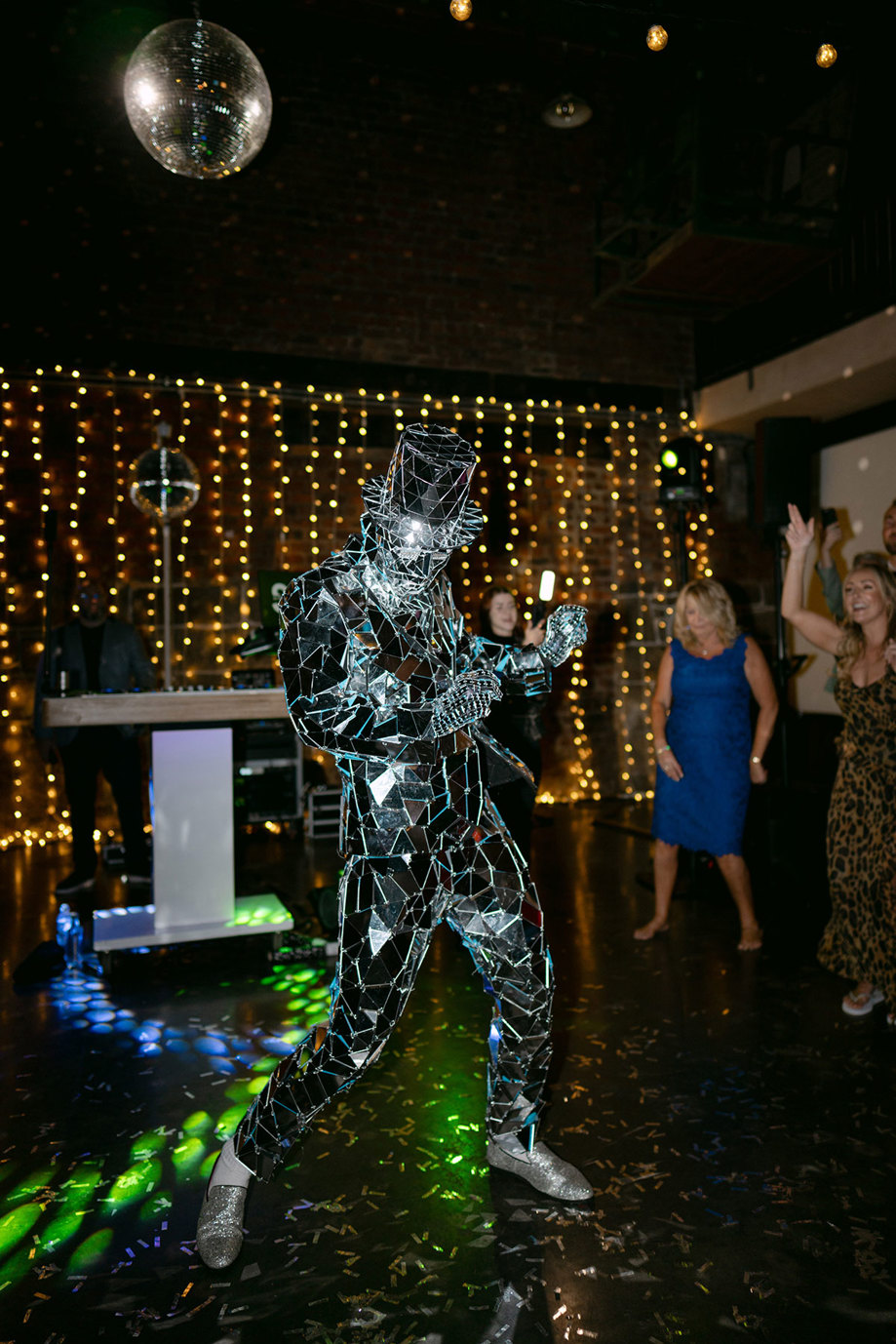 A person dancing in a mirror suit with a hat and glasses 