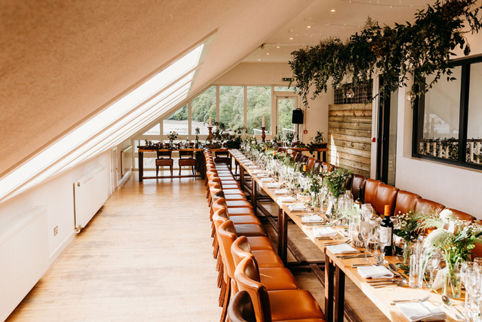 View of the wedding table set with crockery, cutlery, wine and foliage 