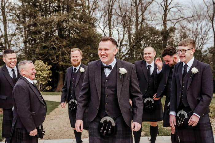 a group of men in dark kilts stand in a group