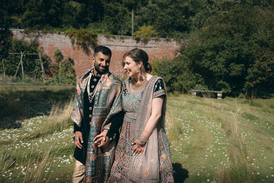 A bride and groom wearing Indian attire walking in the walled garden at Byre of Inchyra.