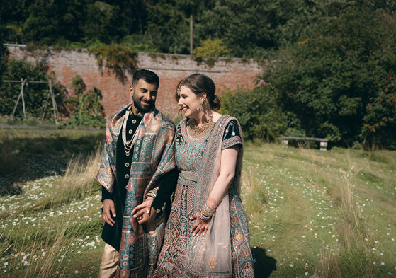 A bride and groom wearing Indian attire walking in the walled garden at Byre of Inchyra.