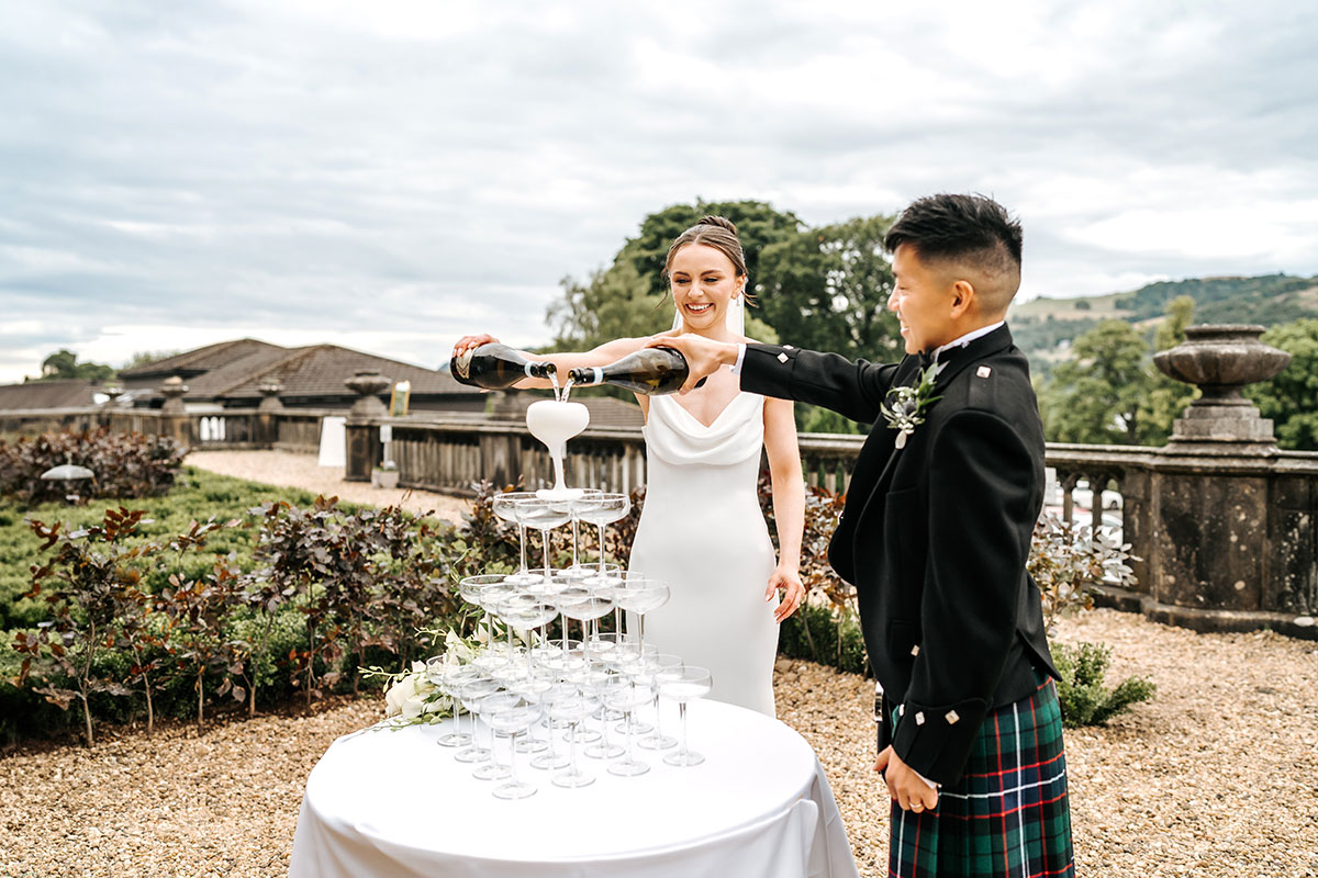 bride and groom pours champagne into tower of glasses at mar hall