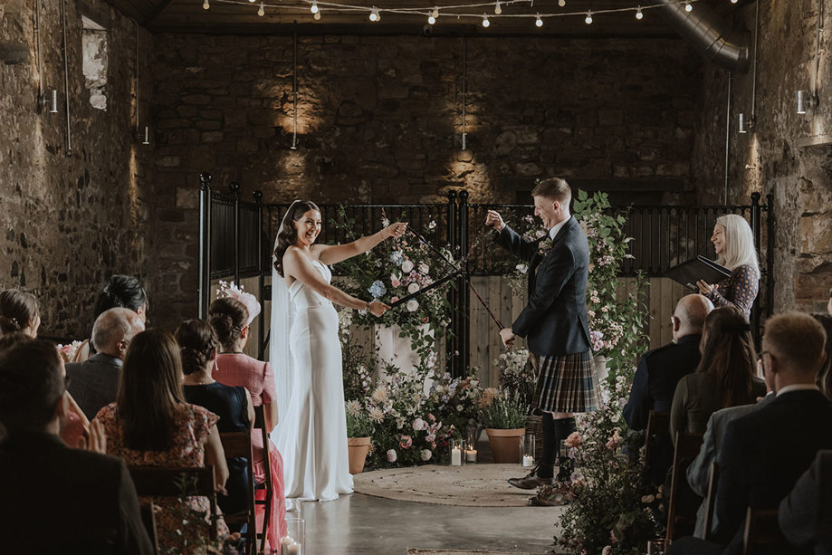 bride and groom conduct hand fasting during wedding ceremony