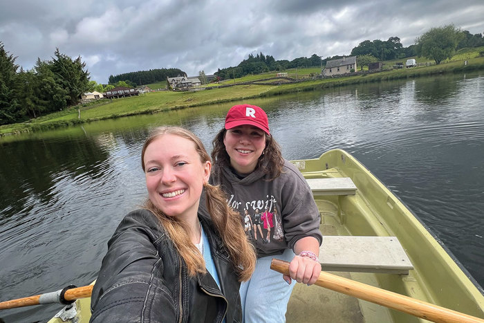 two girls posing for a selfie in a green row boat