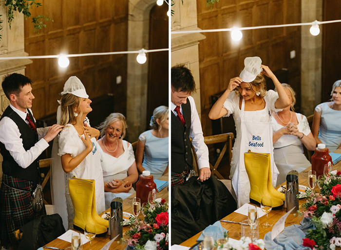 Standing at a table a bride tries on a hair net hat and an apron that says 'Bell's Seafood' 