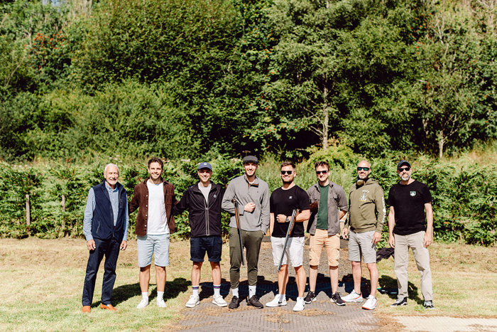 groomsmen line up for photograph ahead of clay pigeon shooting