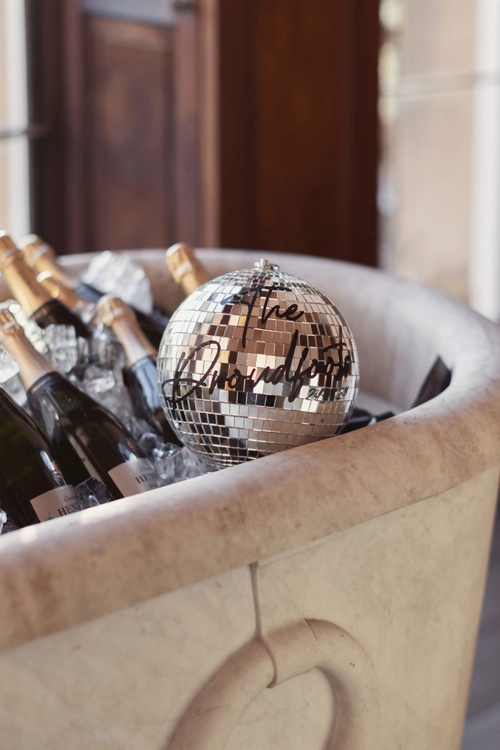 A group of bottles of champagne in a bath with disco ball.