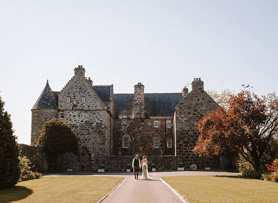 a bride and groom walking hand in hand in the grounds outside Barra Castle