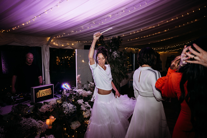 A Person Wearing A White Skirt And Top Dancing While Holding A Glow Stick