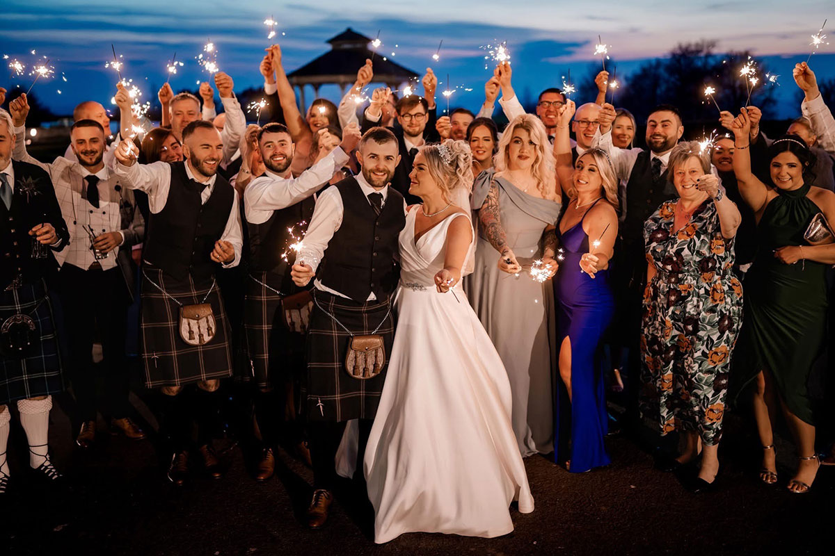 a wedding group shot with sparklers at nighttime at The Vu sustainable central Scotland wedding venue