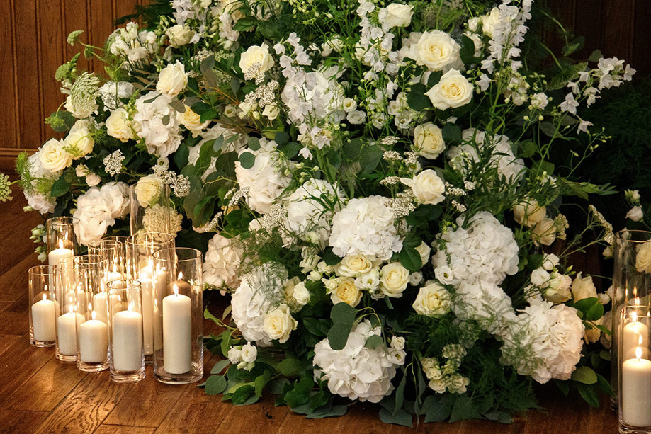 white flowers, green foliage and candles in tall glass jars