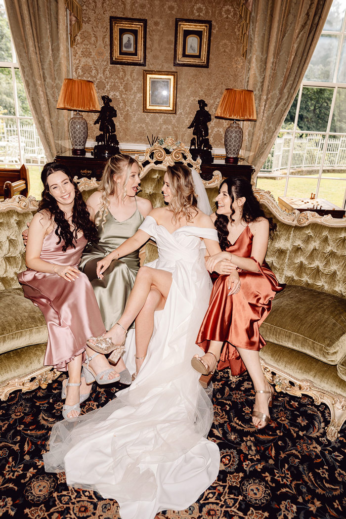 bride laughs while sitting down next to her bridesmaids at drumtochty castle