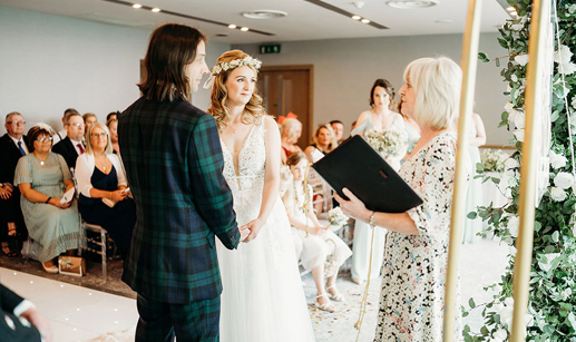 celebrant conducting wedding ceremony of a bride and groom in front of guests