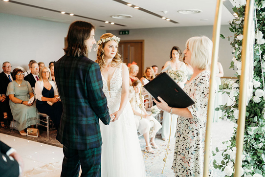 celebrant conducting wedding ceremony of a bride and groom in front of guests