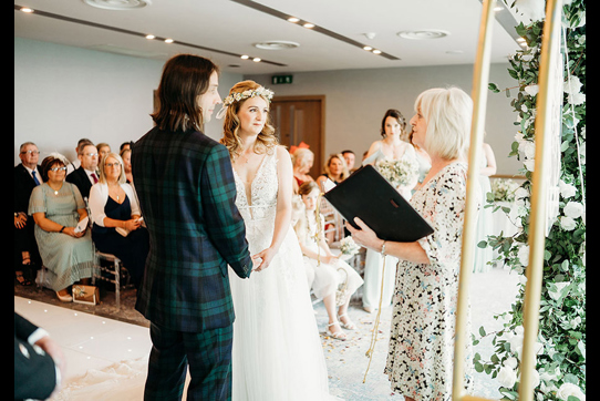 celebrant conducting wedding ceremony of a bride and groom in front of guests