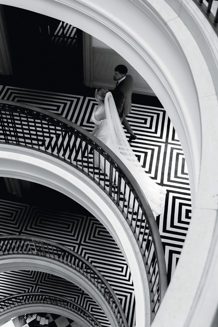 A bride and groom walking down a spiral staircase