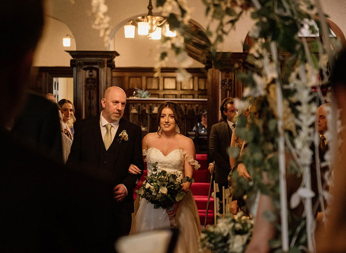 A man and woman linking arms and walking up an aisle 