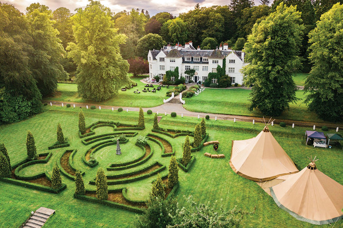 A large white house with a large lawn and a tent