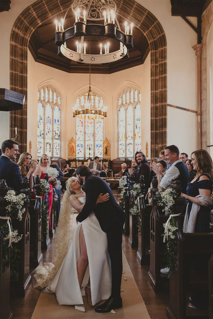 A bride and groom kissing in a church.