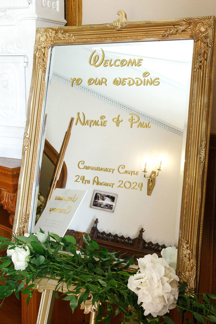 a mirror in an ornate gold frame decorated with Disney lettering and flowers.