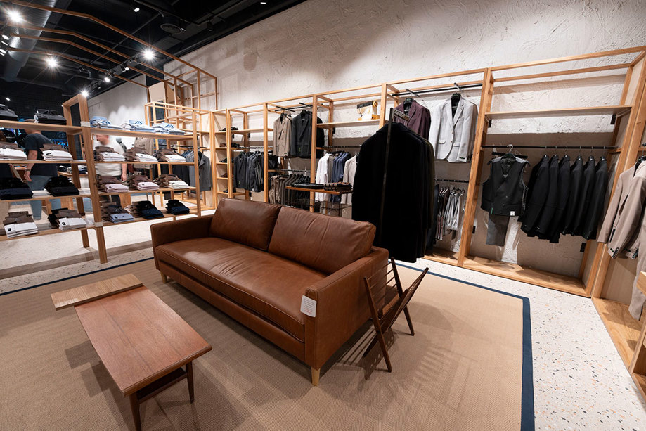 Wooden rails with clothes and a sofa in Remus Uomo Braehead