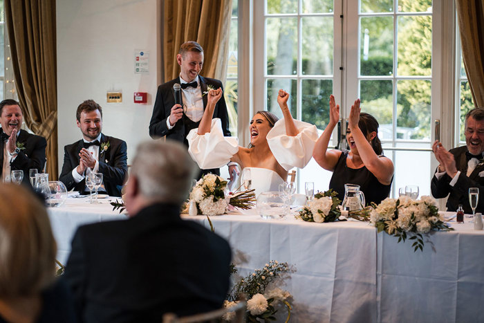 Bride and bridesmaids cheer at grooms speech