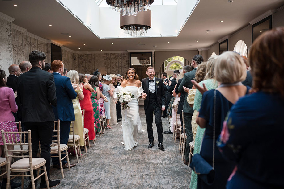 Just married bride and groom happily walking back down the aisle together