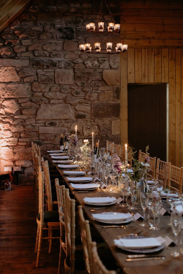 a long wooden table set for a wedding dinner in stone barn at the Byre at Inchrya