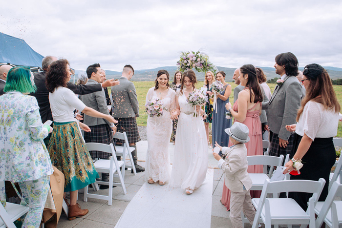 Guests Throwing Confetti At Two Brides After A Same Sex Wedding Ceremony In The Highlands