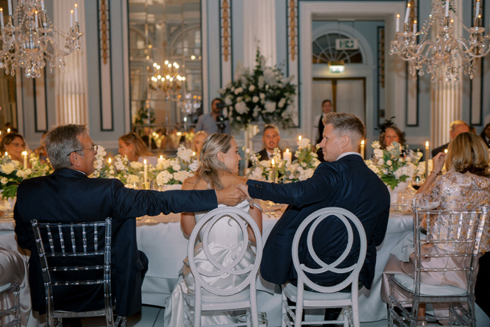 Groom and bride's father shake hands at the table